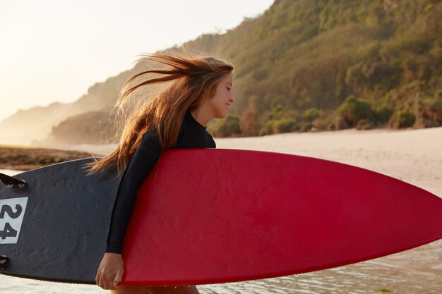 Concepto de personas, naturaleza y estilo de vida activo. Tiro lateral de feliz joven mojado lleva tabla de surf