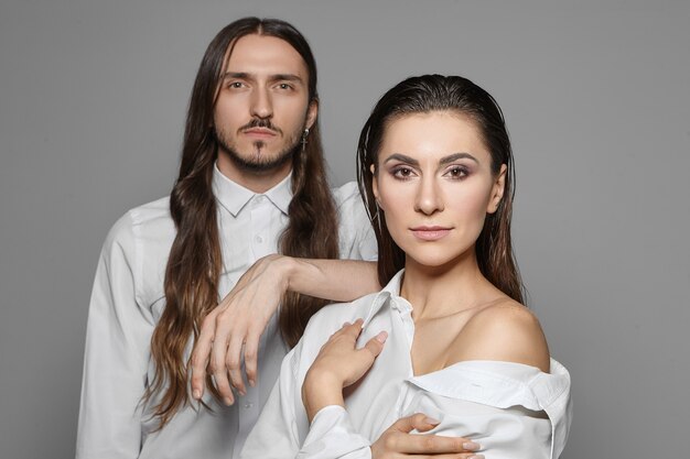 Concepto de personas, relaciones, amor y asociación. Disparo aislado de pareja elegante en camisas blancas posando juntos: chico guapo hipster con barba colocando la mano sobre el hombro de la mujer