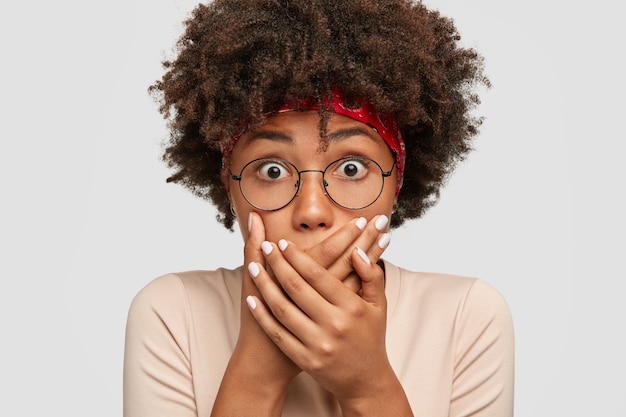 Concepto de personas y sorpresa. Estupefacta joven de piel oscura tiene los ojos abiertos