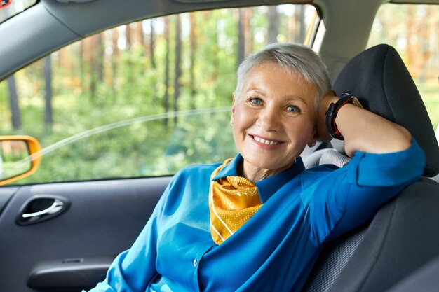 Concepto de personas, transporte, viajes y ocio. Retrato de hermosa mujer de mediana edad elegante sentado cómodamente en el asiento del pasajero