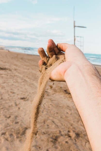 Concepto de playa con mano sujetando arena
