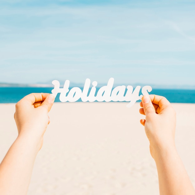 Concepto de playa con manos sujetando letras que ponen holidays