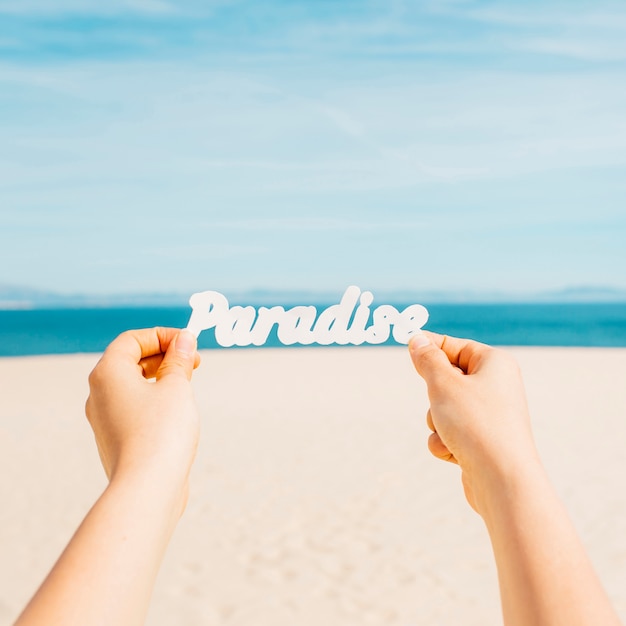 Concepto de playa con manos sujetando letras que ponen paradise