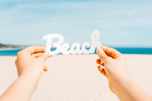 Concepto de playa con manos sujetando letras