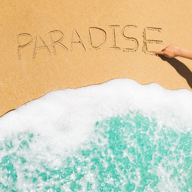 Concepto de playa con el paraíso escrito en la arena