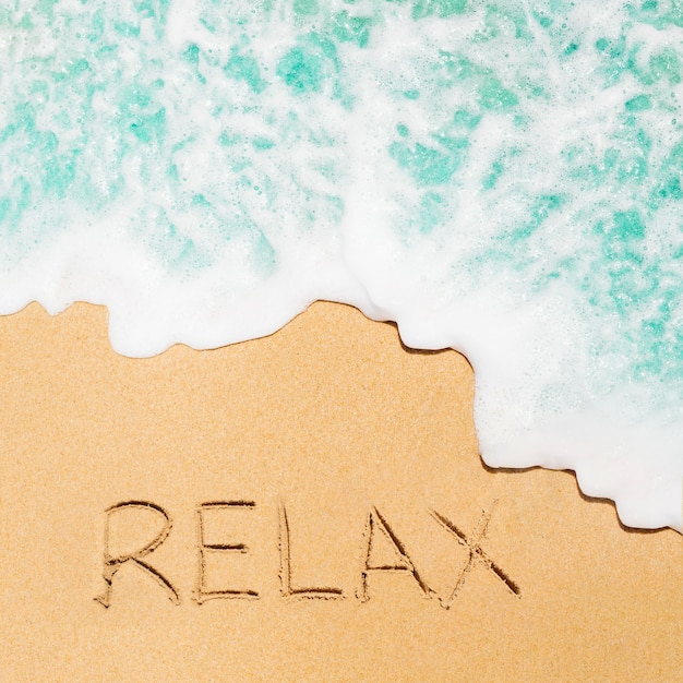Concepto de playa con relajación escrito en arena