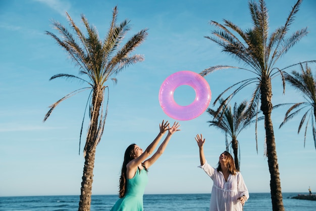 Concepto de playa y verano con mujeres alegres y palmeras