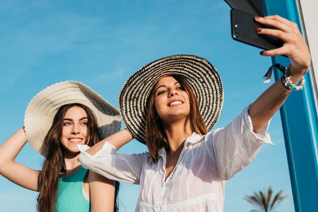 Concepto de playa y verano con mujeres haciendo selfie con smartphone