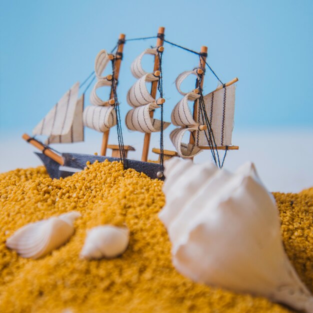 Concepto de playa con vista cercana de conchas y barco de vela