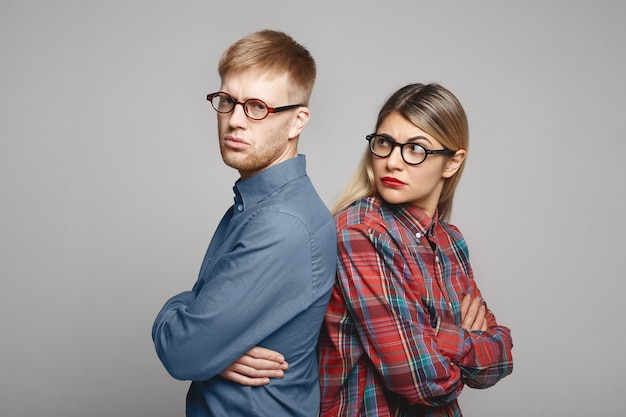 Concepto de problemas de personas, amor, familia, matrimonio y relaciones. Mujer joven gruñona y hombre barbudo de pie espalda con espalda y manteniendo los brazos cruzados después de una pelea seria