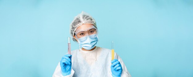 Concepto de pruebas médicas y de laboratorio sonriente doctora asiática trabajadora de laboratorio que muestra tubos con clini