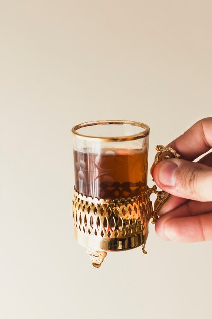 Concepto de ramadán con mano sujetando vaso de té