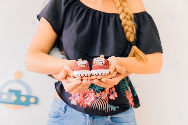 Concepto de recién nacido con mujer sujetando zapatos de bebé