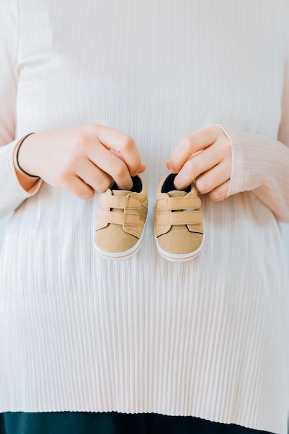 Concepto de recién nacido con mujer sujetando zapatos