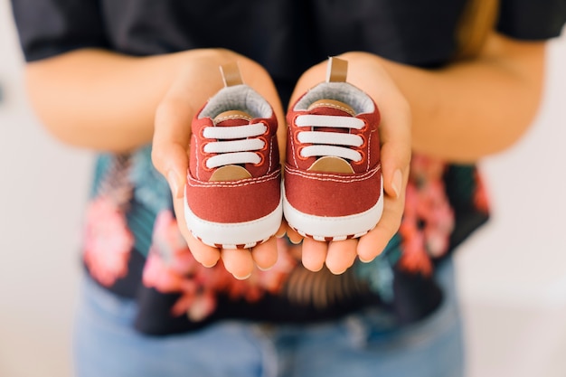 Concepto de recién nacido con mujer con zapatos chicos en las manos