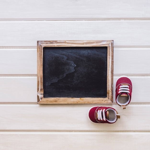 Concepto de recién nacido con zapatos pequeños y pizarra