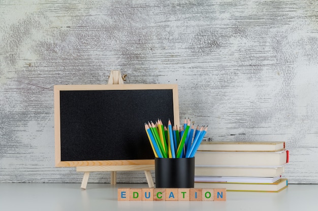 Concepto de regreso a la escuela con pizarra, lápices, libros, texto educativo en cubos de madera en blanco