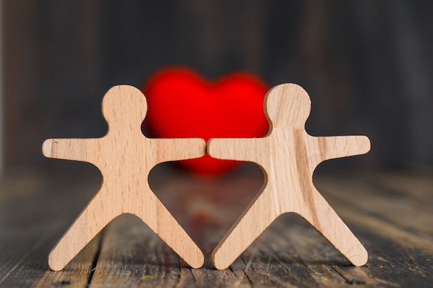 Concepto de relación con corazón rojo, figuras humanas de madera en vista lateral de la mesa de madera.