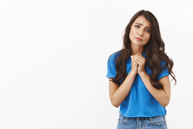 Concepto de romance de ternura Encantadora chica morena linda y romántica con camiseta azul se toman de la mano frunciendo el ceño y mirando a la cámara con una expresión tocada conmovedora simpatizar