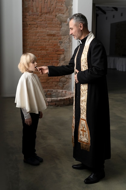 Concepto de la sagrada comunión con niño y sacerdote tiro completo