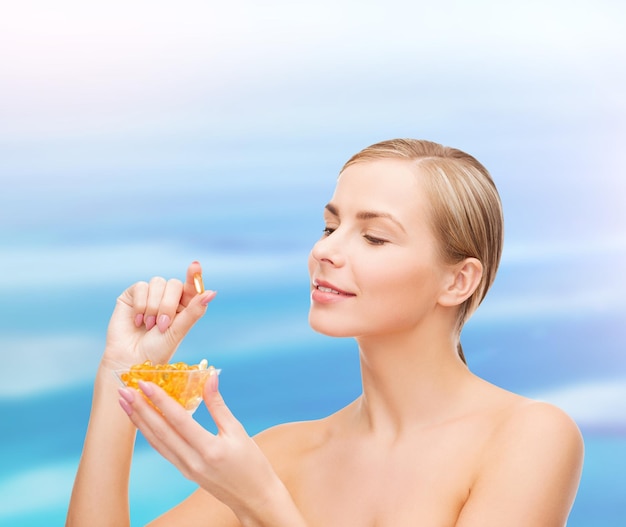 Concepto de salud y belleza - mujer encantadora con vitaminas omega 3