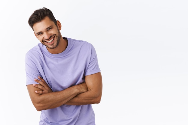 Foto gratuita concepto de salud, estilo de vida y emociones de los hombres. chico barbudo sonriente atractivo alegre en camiseta morada, riendo inclina la cabeza hacia adelante y sonriendo con sonrisa sexy, brazos cruzados sobre el pecho