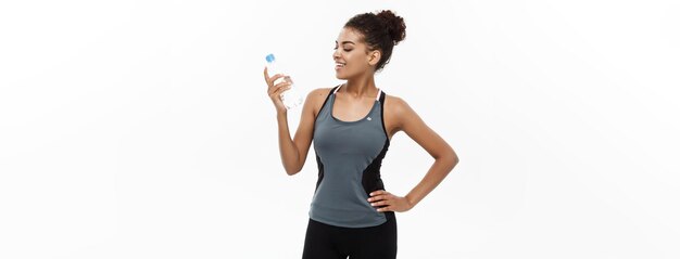 Concepto de salud y fitness hermosa chica afroamericana en ropa deportiva con agua plástica