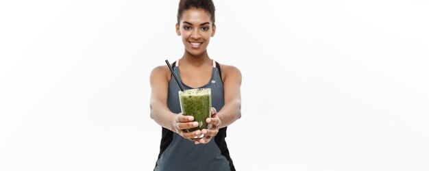 Concepto de salud y fitness Hermosa dama africana americana en ropa de fitness bebiendo bebida vegetal saludable aislada sobre fondo blanco