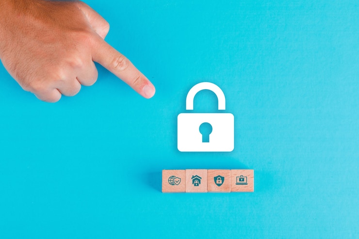 Foto gratuito concepto de seguridad con bloques de madera, icono de candado de papel en plano de mesa azul. mano de hombre apuntando.