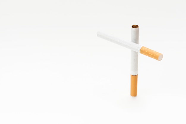 Concepto de signo cruzado hecho de cigarrillo sobre fondo blanco