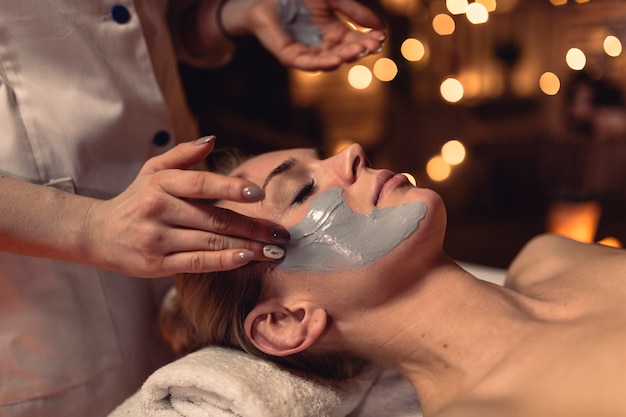 Concepto de spa con mujer con crema en la cara