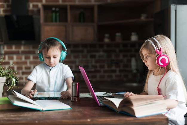 Foto gratuita concepto de tecnología con dos niños sentados en mesa