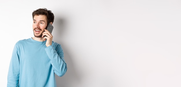Foto gratuita concepto de tecnología hombre alegre hablando por teléfono móvil con llamada telefónica y mirando suplente divertido