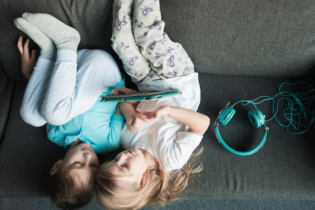 Foto gratuita concepto de tecnología con niños tumbados en sofá