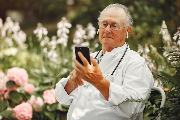 Concepto de tecnología, personas y comunicación. Hombre mayor en el parque de verano. Doctor usando un teléfono.