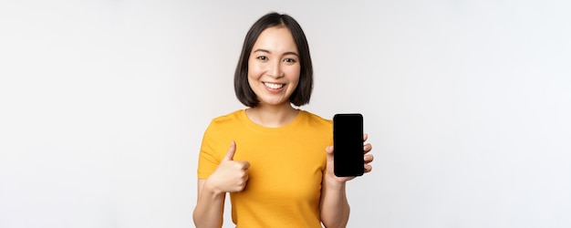 Concepto de tecnología y personas joven sonriente que muestra el pulgar hacia arriba y el teléfono móvil de la pantalla del teléfono inteligente