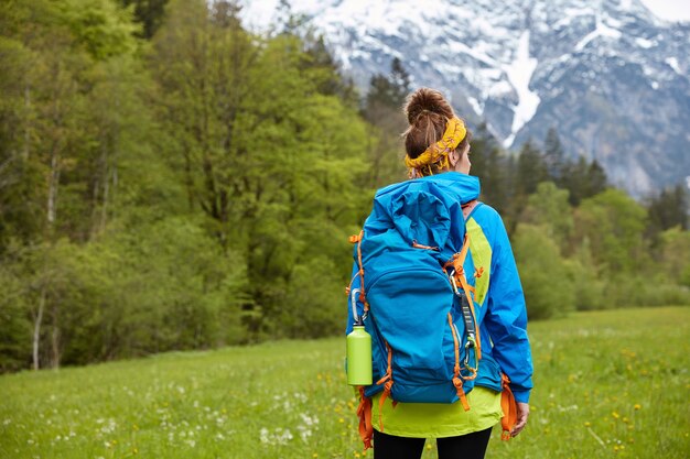 Concepto de trekking, deambular y senderismo. Excursionista de mujer activa posa en la cima de la colina, pasea contra el paisaje de montaña, tiene descanso activo