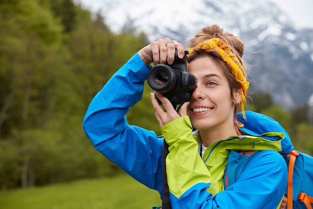 Concepto de turismo, afición y aventura. Joven turista positivo toma una imagen del paisaje escénico con una cámara profesional