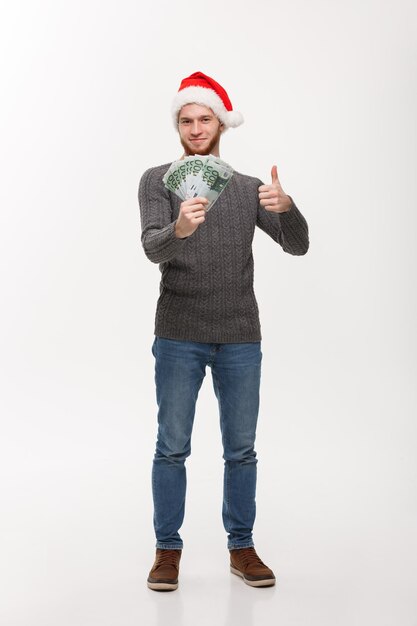 Concepto de vacaciones barba joven hombre con dinero delante sobre fondo blanco.