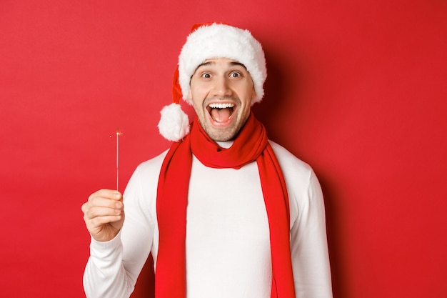 Concepto de vacaciones de invierno de navidad y celebración de primer plano de hombre guapo feliz con sombrero de santa y sombrero de santa.