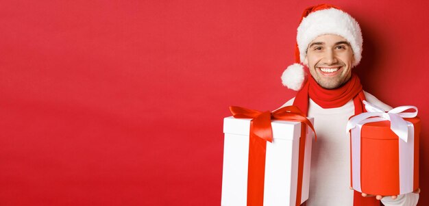 Concepto de vacaciones de invierno navidad y estilo de vida primer plano de chico guapo sonriente con sombrero de santa y ...