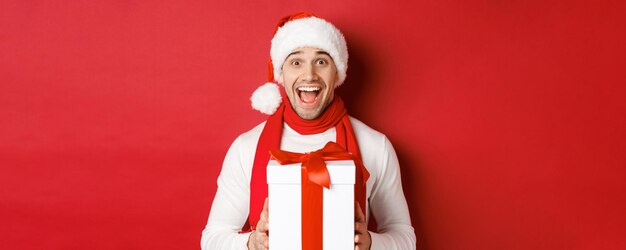 Concepto de vacaciones de invierno navidad y estilo de vida primer plano de hombre guapo emocionado en santa jat y...