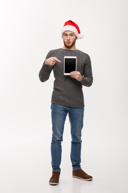 Concepto de vacaciones y negocios Hombre guapo joven que muestra la pantalla de la tableta y presenta con el dedo acusador