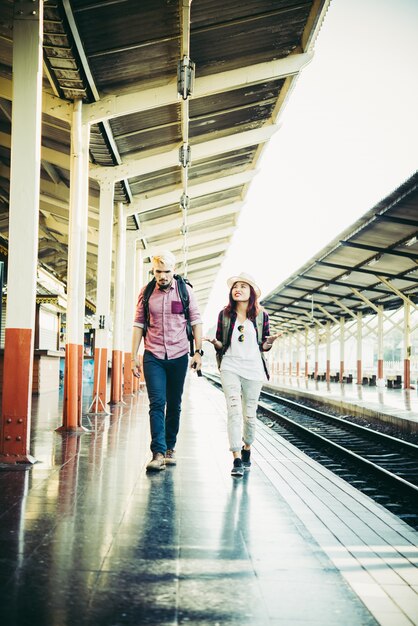 Concepto de vacaciones de pareja: Pareja joven hipster en la estación de tren.