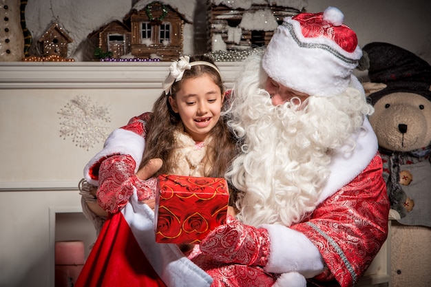 Concepto de vacaciones y personas - niña sonriente con santa claus