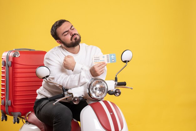 Concepto de viaje con ambicioso hombre sentado en motocicleta con maleta mostrando boleto en amarillo