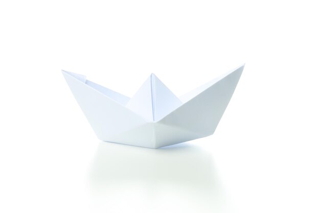 Concepto de viaje y aventura con barco de papel aislado sobre fondo blanco.