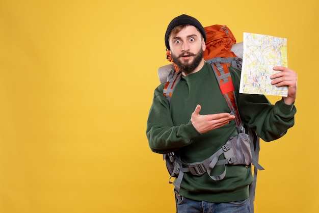 Concepto de viaje con chico joven preguntándose con packpack y sosteniendo el mapa en amarillo