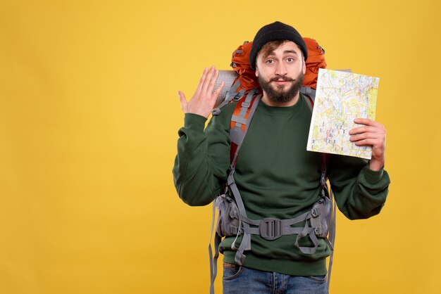 Concepto de viaje con chico joven seguro con packpack y sosteniendo el mapa que aparece en amarillo