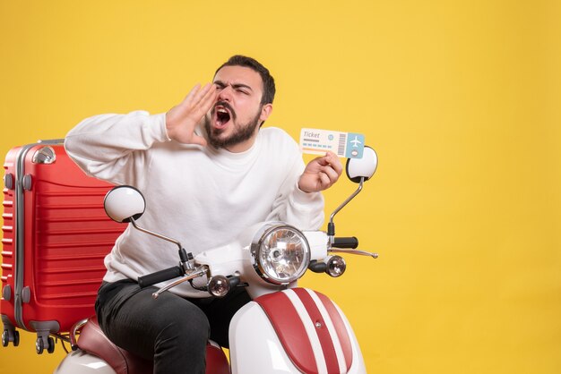 Concepto de viaje con hombre nervioso sentado en motocicleta con maleta llamando a alguien en amarillo